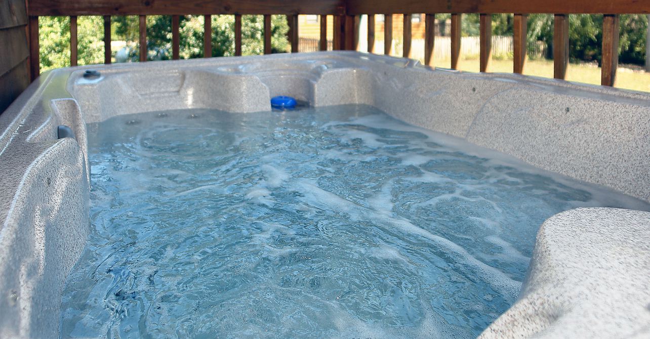A bubbling hot tub on the deck of a cabin.